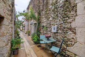 an alley with a table and chairs next to a stone wall at Le Cocon d'Eymet village in Eymet