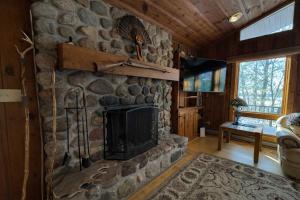 a living room with a stone fireplace in a cabin at Stack's Back Bay Retreat in Minocqua