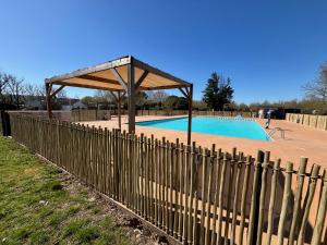 a fence around a swimming pool with a wooden pavilion at Luberon Detente Mobile Home in Cheval-Blanc