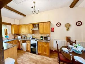 a kitchen with wooden cabinets and a dining room table at Very spacious rural 2 bed barn sleeps 5 in Usk