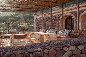 a patio with tables and chairs and a stone wall at Hotel Vestige Binidufà in Isla de Menorca