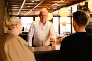 a man standing at a bar with a glass of wine at De Herbergh van Flielant in Oost-Vlieland