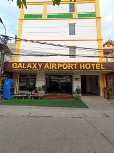 a person sitting on a bench in front of a hotel at Galaxy Airport Hotel in Hanoi