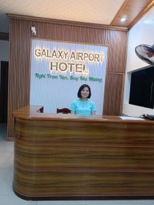 a woman standing at a podium in front of a sign at Galaxy Airport Hotel in Hanoi