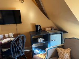 a living room with a table and a small refrigerator at Under The Thatch at Rose House in Iwerne Minster