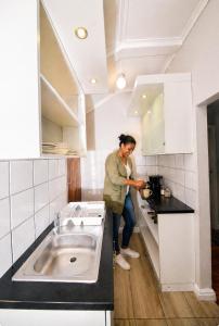 a woman standing in a kitchen preparing food at Luxury Backpackers in Port Elizabeth