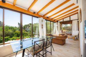 a dining room with a glass table and glass chairs at Cel Pins in Portopetro