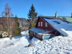 a red barn is covered in snow at Chalupa pod smrky in Bedřichov