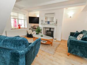 a living room with two blue couches and a table at September Cottage in Weymouth