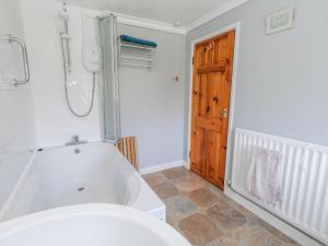a bathroom with a bath tub and a toilet at September Cottage in Weymouth +29 photos