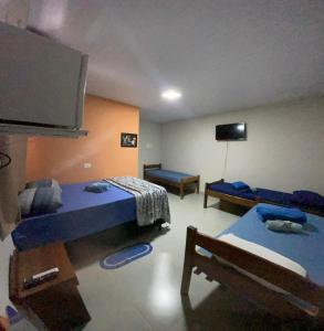 a room with two beds and a flat screen tv at POUSADA ORTEGA in Bodoquena