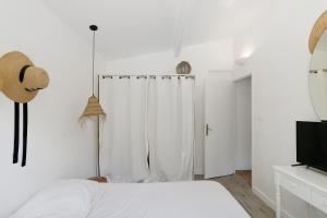 a white bedroom with a bed and a shower at Mer et montagne à Conca in Conca