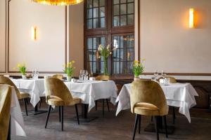 a restaurant with white tables and chairs and a chandelier at Manoir de Lébioles in Spa