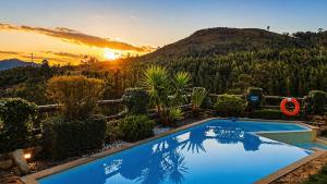 a swimming pool with a sunset in the background at Casa Favo de Mel - Jacuzzi & Piscina - Refúgio na Montanha in Arcos de Valdevez