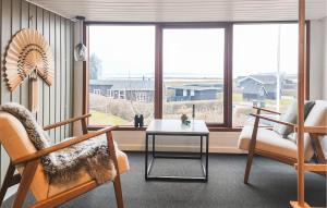 a living room with a chair and a table and windows at 2 Bedroom Nice Home In Juelsminde in Juelsminde
