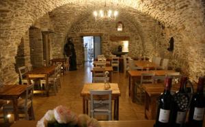 a restaurant with wooden tables and bottles of wine at Les Chambres Cast'elles in Malves