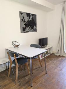 a table and chairs in a room with a tv at Au Marron in Seissan