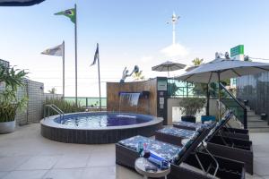 a pool with chairs and umbrellas on a rooftop at Hotel Golden Park Recife Boa Viagem By Nacional Inn in Recife