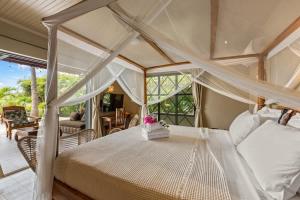 a bedroom with a canopy bed and a patio at Bali Suites - Ubud Suite in Willemstad