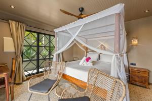 a bedroom with a canopy bed and two chairs at Bali Suites - Ubud Suite in Willemstad +14 photos