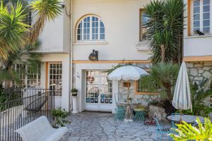 a house with a patio with an umbrella and chairs at Le Val Duchesse Hotel & Appartements in Cagnes-sur-Mer