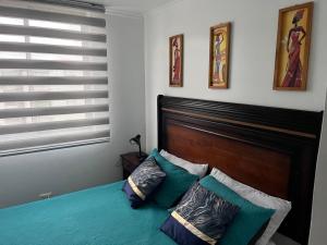 a bedroom with a bed with a wooden headboard and pillows at Playa de Dichato in Dichato