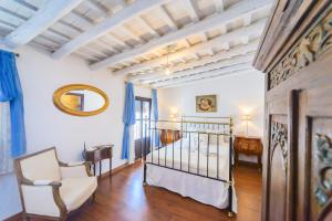 a room with a bed and a chair and a mirror at Casa de la Robledo in Peñaflor +22 photos