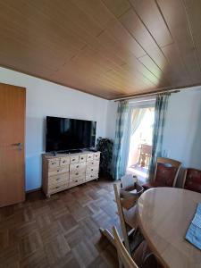a living room with a flat screen tv and a table at Gästehaus Kienle in Rot an der Rot