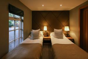 two beds in a room with a window at Grand Fir Lodge - The Hollies Retreats in Tarporley