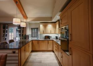 a large kitchen with wooden cabinets and black counter tops at Grand Fir Lodge - The Hollies Retreats in Tarporley
