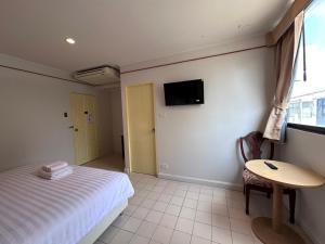 a bedroom with a bed and a table and a tv at Baan Smile in Patong Beach
