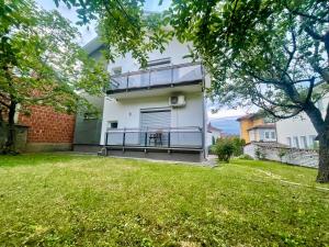 a white house with a balcony and a yard at Cozy Home in Peje