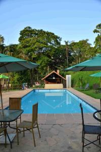 a swimming pool with chairs and tables and umbrellas at Hotel fazenda do Cedro in Areal