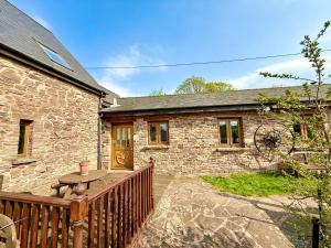 a stone house with a wooden fence and a table at Very spacious rural 2 bed barn sleeps 5 in Usk