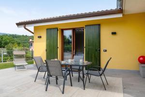 a patio with a table and chairs and a yellow house at Casa Elisa in Torri del Benaco