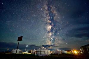 a starry night with a large white domes in a field at Mongol Altai Tour Camp in Högönö-Taranaiin-Hüree