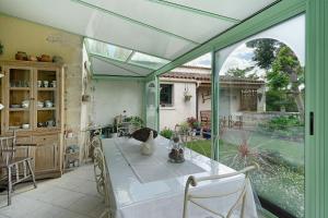 a conservatory with a table and a glass extension at Chambres Escale Pontilabienne in Pont-lʼAbbé-dʼArnoult