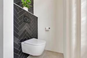 a white toilet in a bathroom with a black tile wall at The Velvet Suite Alkmaar in Alkmaar