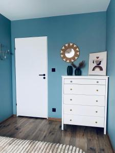 a room with a white dresser and a blue wall at Apartament u Liska in Rumia