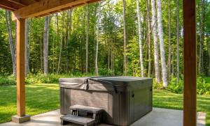 a barbecue under a gazebo with a bench and trees at Spa Pool Table & Comfort - Chalet le Barista in Brownsburg