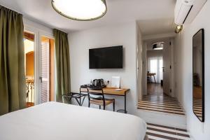 a bedroom with a bed and a desk and a television at Valesmeralda Boutique Rooms, Porto Cervo Marina Adults only in Porto Cervo