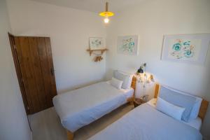 a bedroom with two beds and a door and a lamp at Agapito's Houses in Praia de Odeceixe