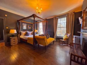 a bedroom with a canopy bed and a yellow chair at The Fat Badger in York