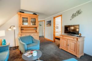 a living room with a tv and a chair and a table at Haus-Margarete-Nordwind in Kampen