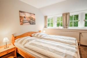 a bedroom with a bed and two windows at Haus-Margarete-Nordwind in Kampen