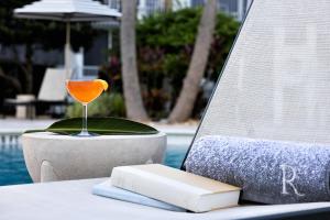 a drink and a book on a table next to a pool at Renaissance Orlando Resort - Disney Springs Area - Free Shuttle & Early Entry to Disney Theme Parks in Orlando +112 photos
