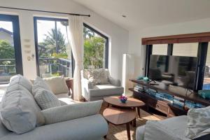 a living room with two couches and a tv at Malee Beach F1 in Phra Ae beach