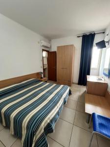 a bedroom with a bed and a desk and a chair at Hotel Il Timone in Specchiolla