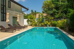 a swimming pool with two chairs and a house at Malee Beach F1 in Phra Ae beach