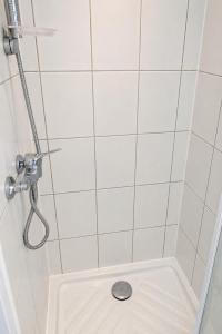 a white tiled shower with a drain in the floor at Appartement bien-être in Liège
